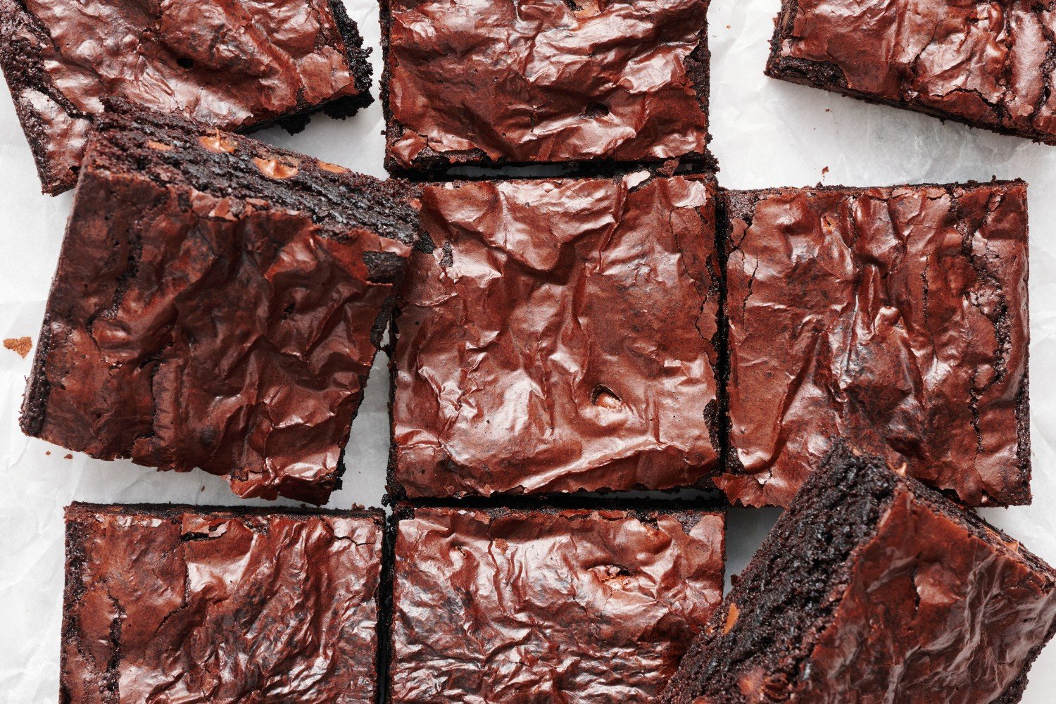 slices of brownies on a marble surface, with some placed at an angle to see the dense, chewy interior.