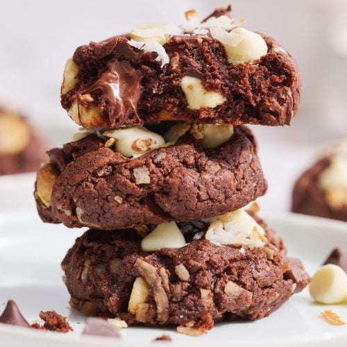 stack of chocolate coconut cookies, top cookie with a bite taken out