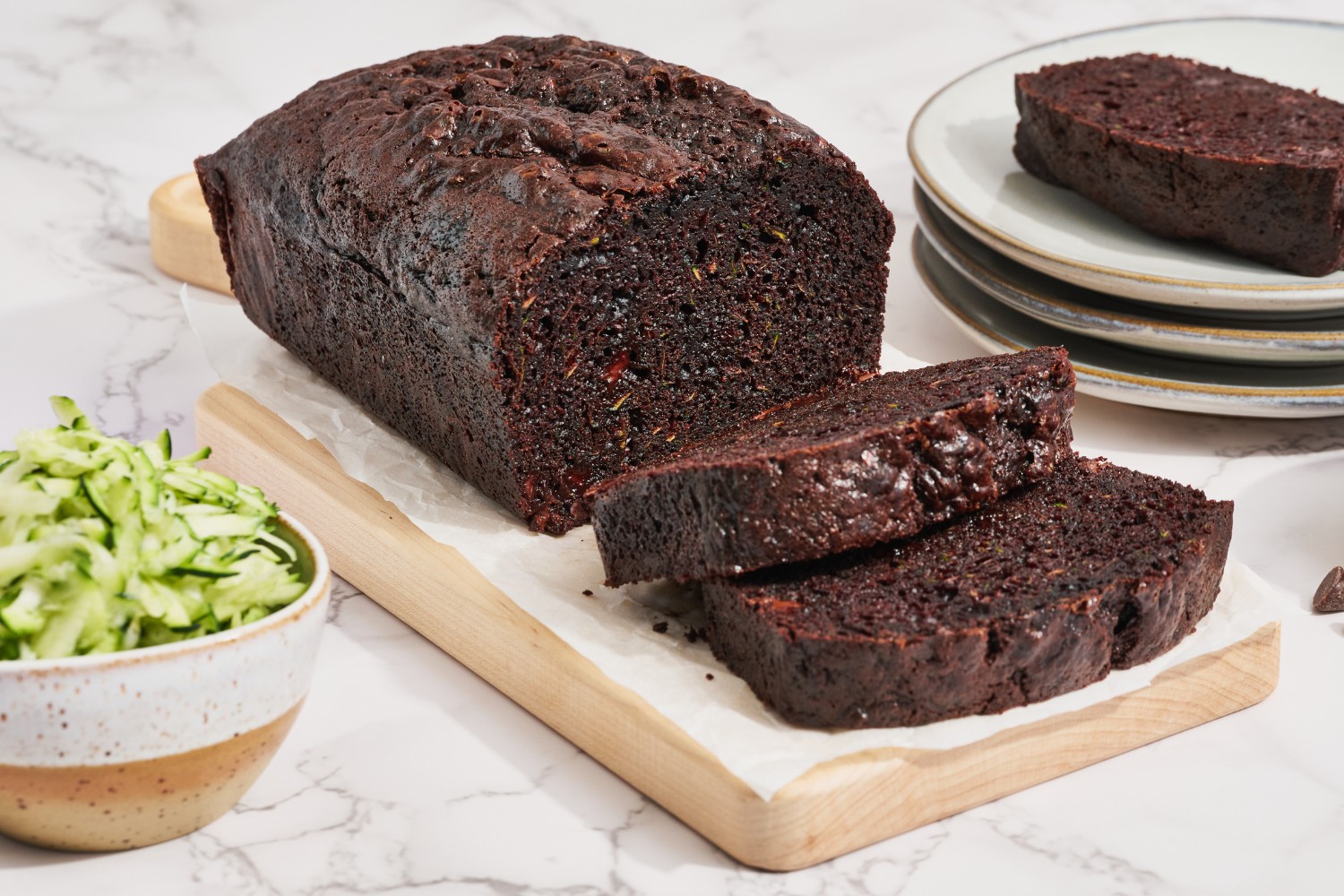 chocolate zucchini bread being sliced on a wooden cutting board.