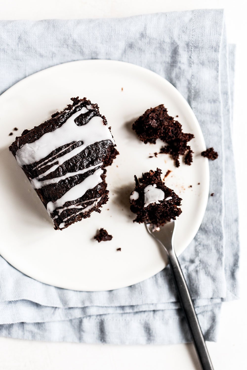 Piece of chocolate zucchini snack cake on a plate with a fork