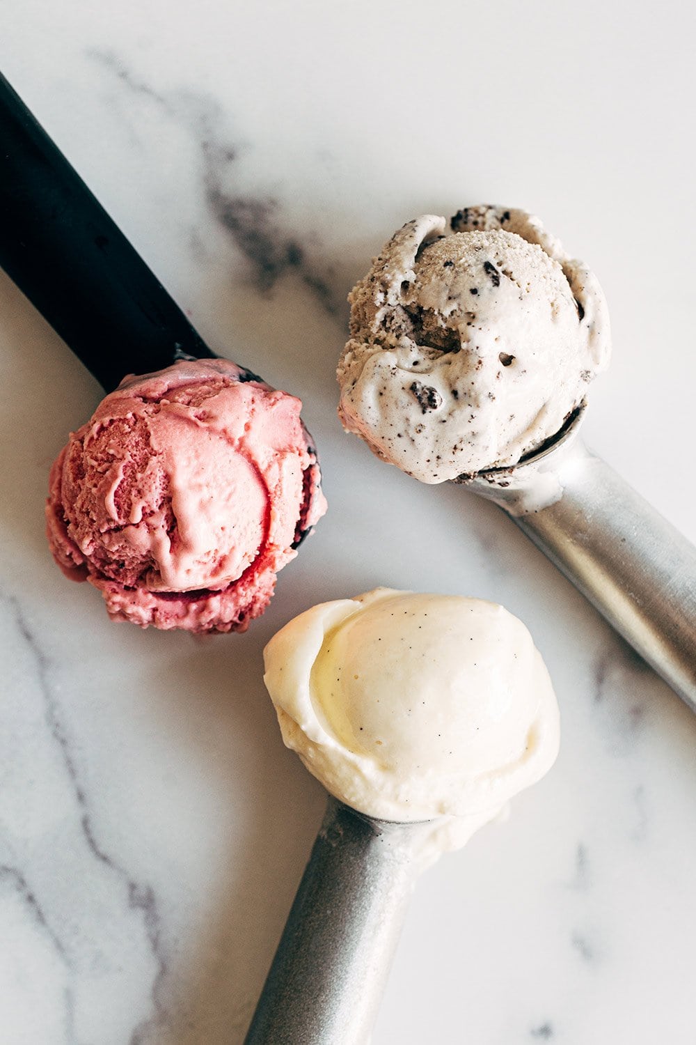 three scoops of creamy homemade ice cream - raspberry, cookies and cream, and vanilla