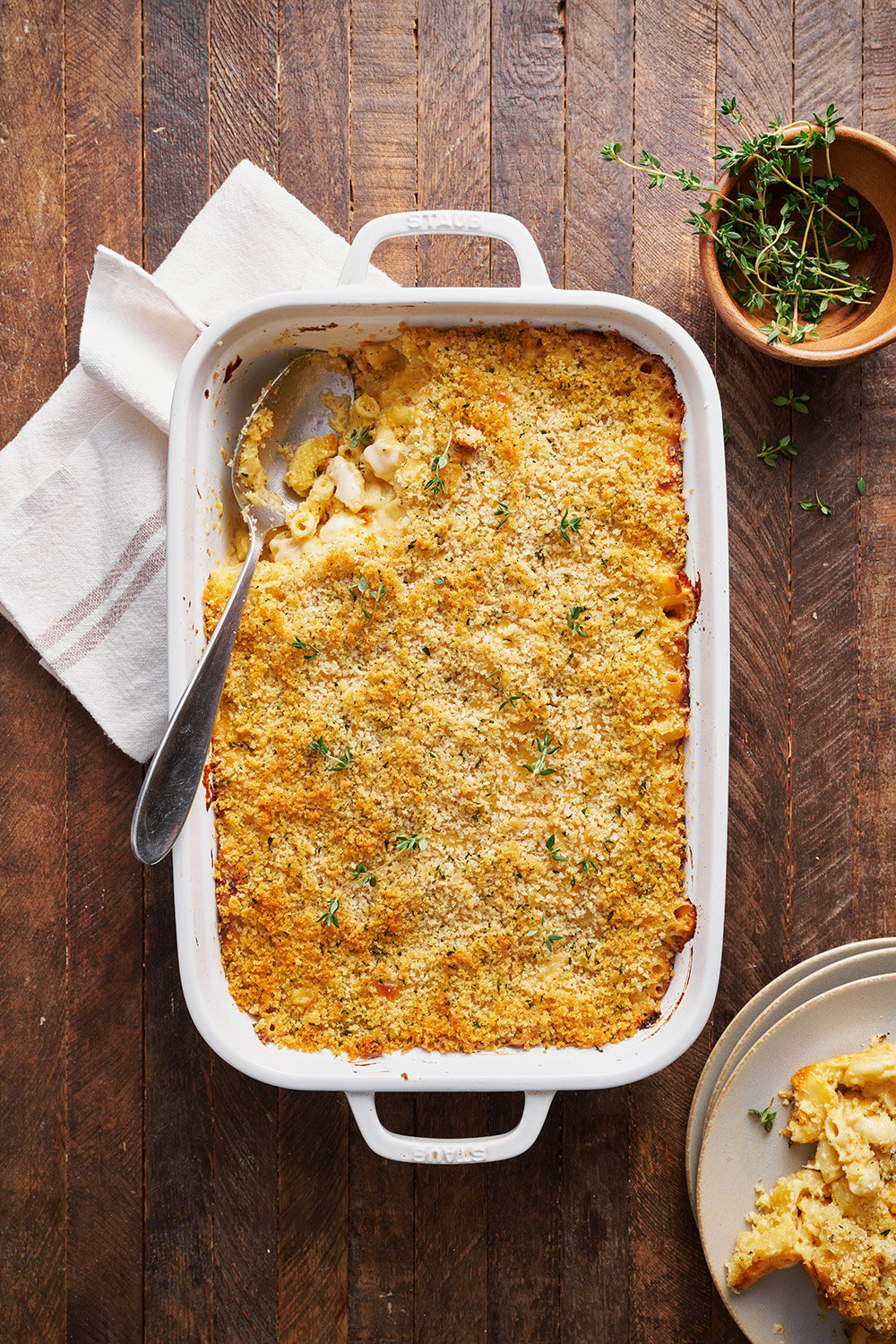 a dish of mac & cheese in a baking pan, with a large spoon, ready to serve.