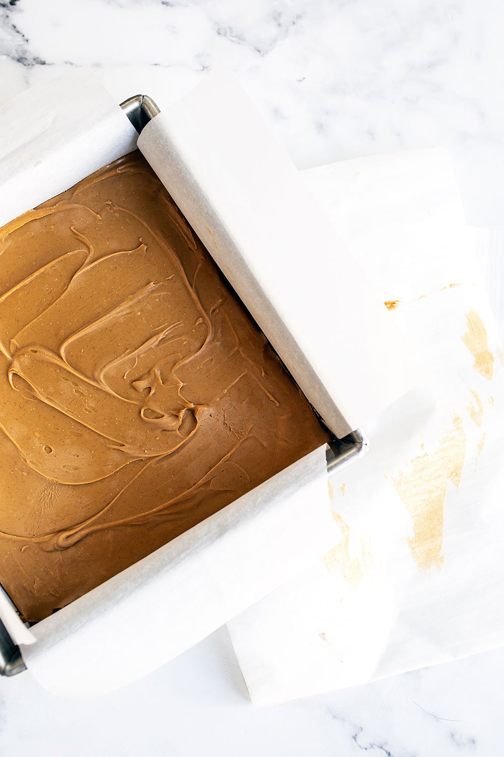 Sheet of frozen peanut butter in a parchment-lined metal pan