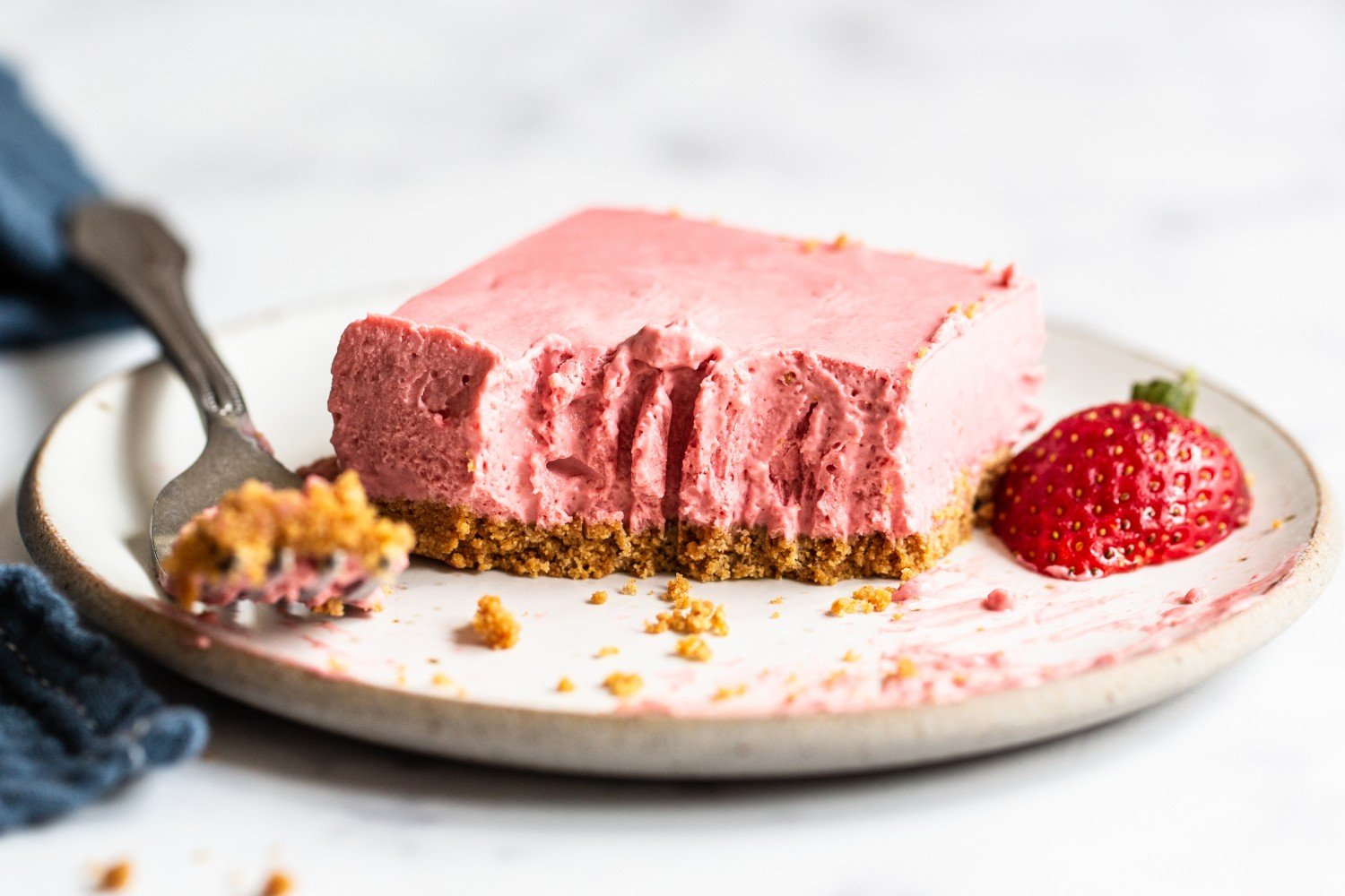 a slice of cheesecake on a plate with a bite taken out.