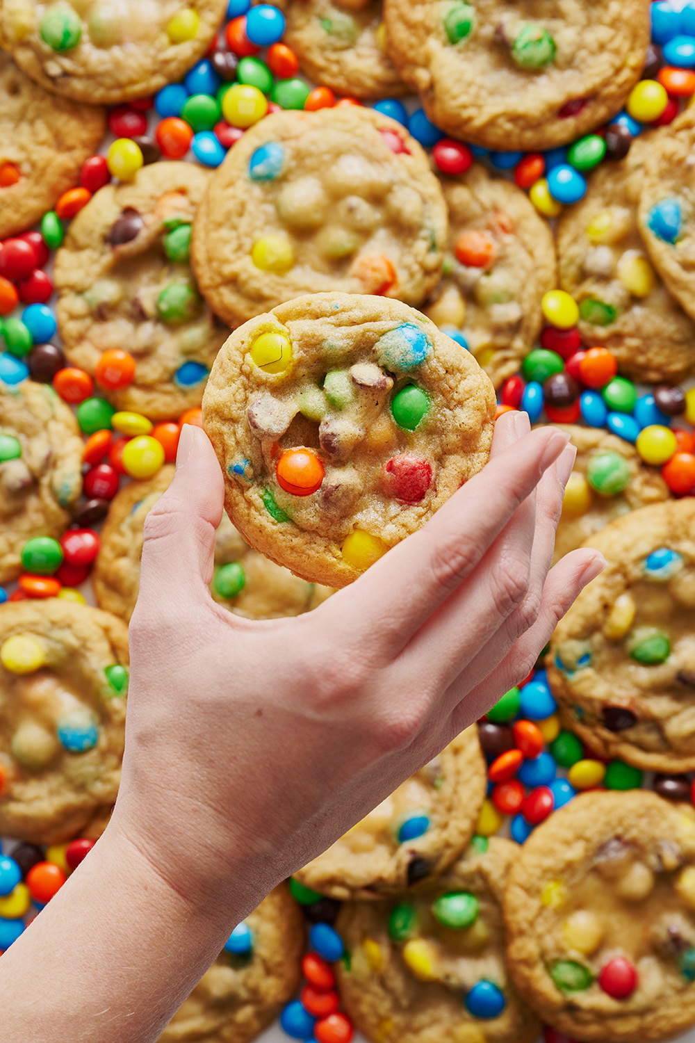 a hand holding up one M&M cookie.