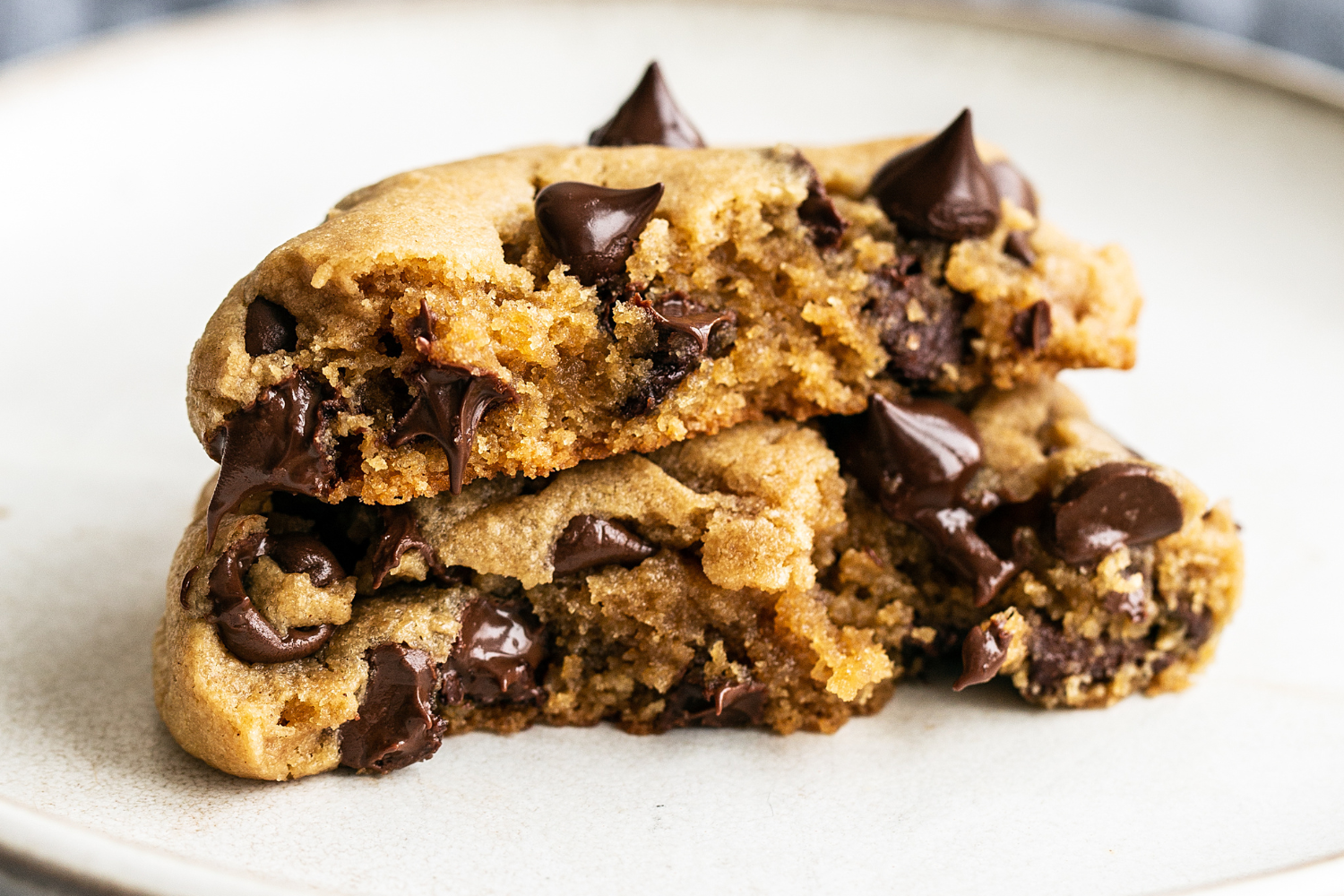 a peanut butter chocolate chip cookie, broken in half and sitting on a plate.