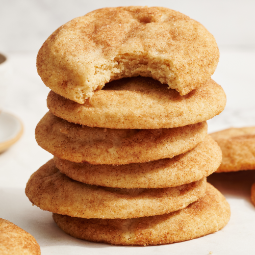 snickerdoodle cookies stacked 6 high, with the top cookie with a bite taken out.