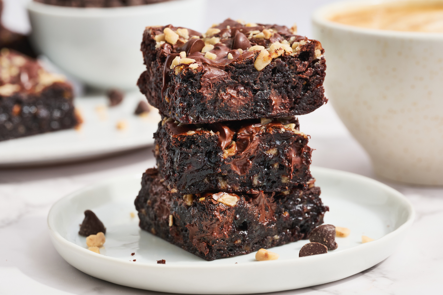 three brownies stacked on a white plate.